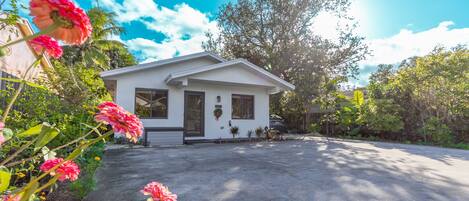 A single-story house with a front porch, a driveway, and a well-maintained garden with flowering plants.
