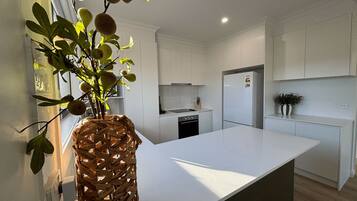A modern kitchen with white cabinetry, a large island, and a woven basket with fruit.
