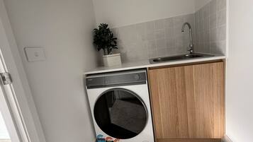 A compact kitchen with a built-in washing machine, a sink, and a potted plant.