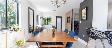 A modern dining area with a wooden table, blue chairs, and a geometric light fixture.