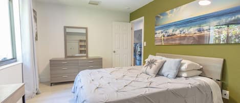 A bedroom with a bed, a dresser, a mirror, and a painting on the wall.