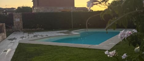 A swimming pool with a grassy area and a building in the background.