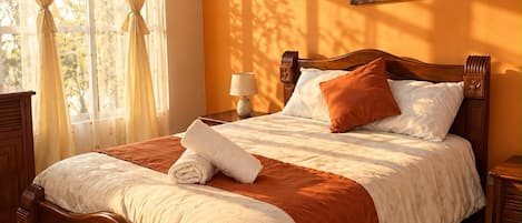 A neatly made bed with a brown headboard, white bedding, and a folded towel.