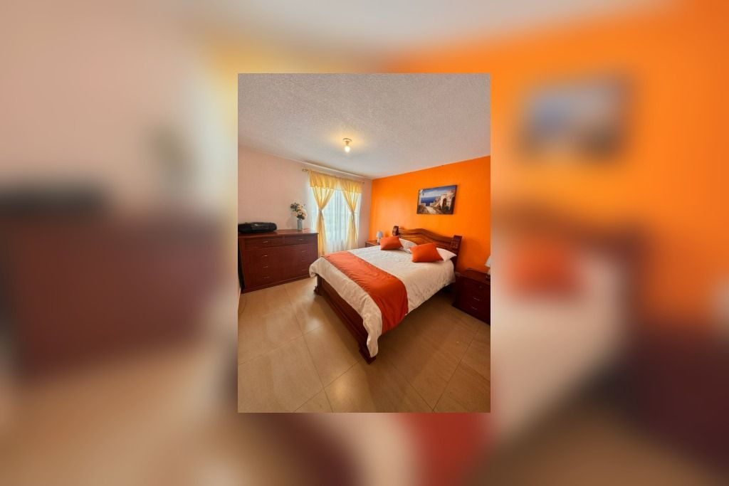 Une chambre à coucher avec un lit, une table de chevet, une commode et une fenêtre avec des rideaux.