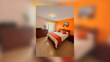 Une chambre à coucher avec un lit, une table de chevet, une commode et une fenêtre avec des rideaux.