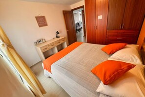 A bedroom with a bed, a desk, and a wardrobe.