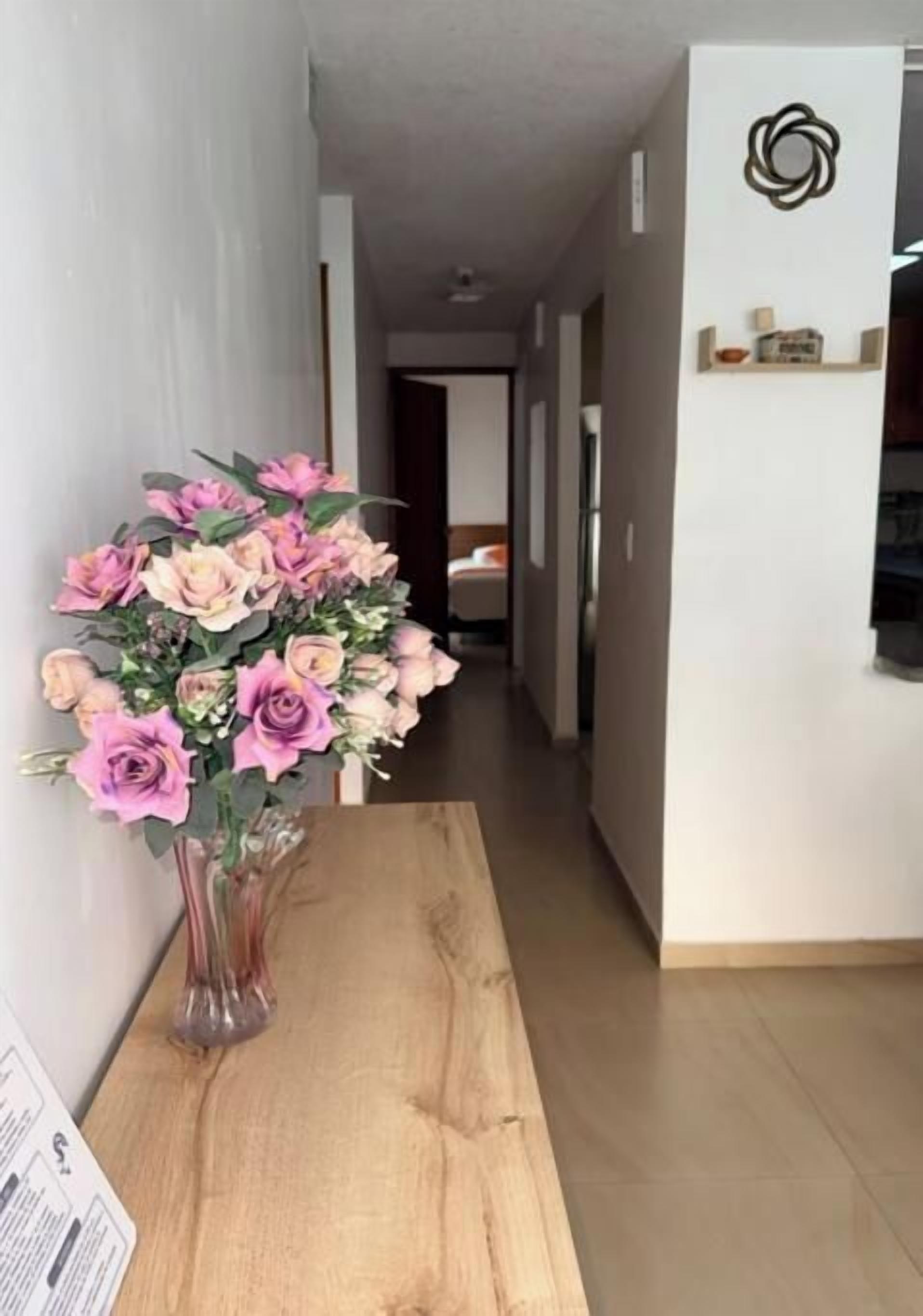Un couloir avec une table en bois et un vase de fleurs.