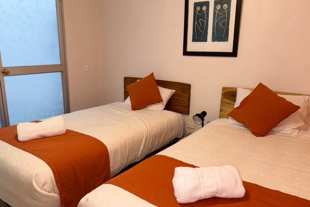 Two single beds with brown and white bedding, a wooden headboard, and a framed artwork on the wall.