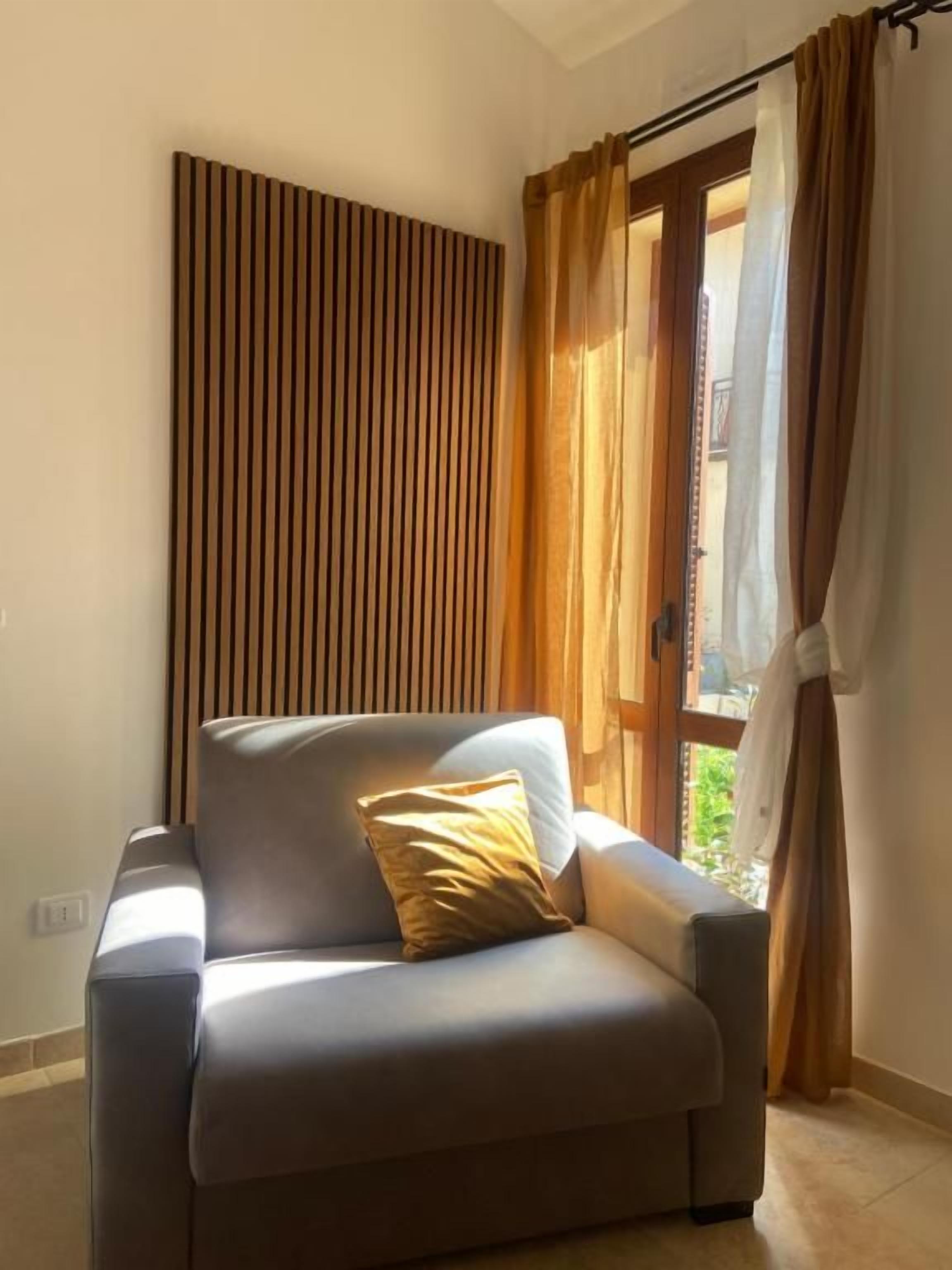 A room with a sofa, a window with curtains, and a wooden panel on the wall.