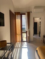 Habitación de hotel con cama, una mesa y una silla. Hay una puerta que da a un balcón.
