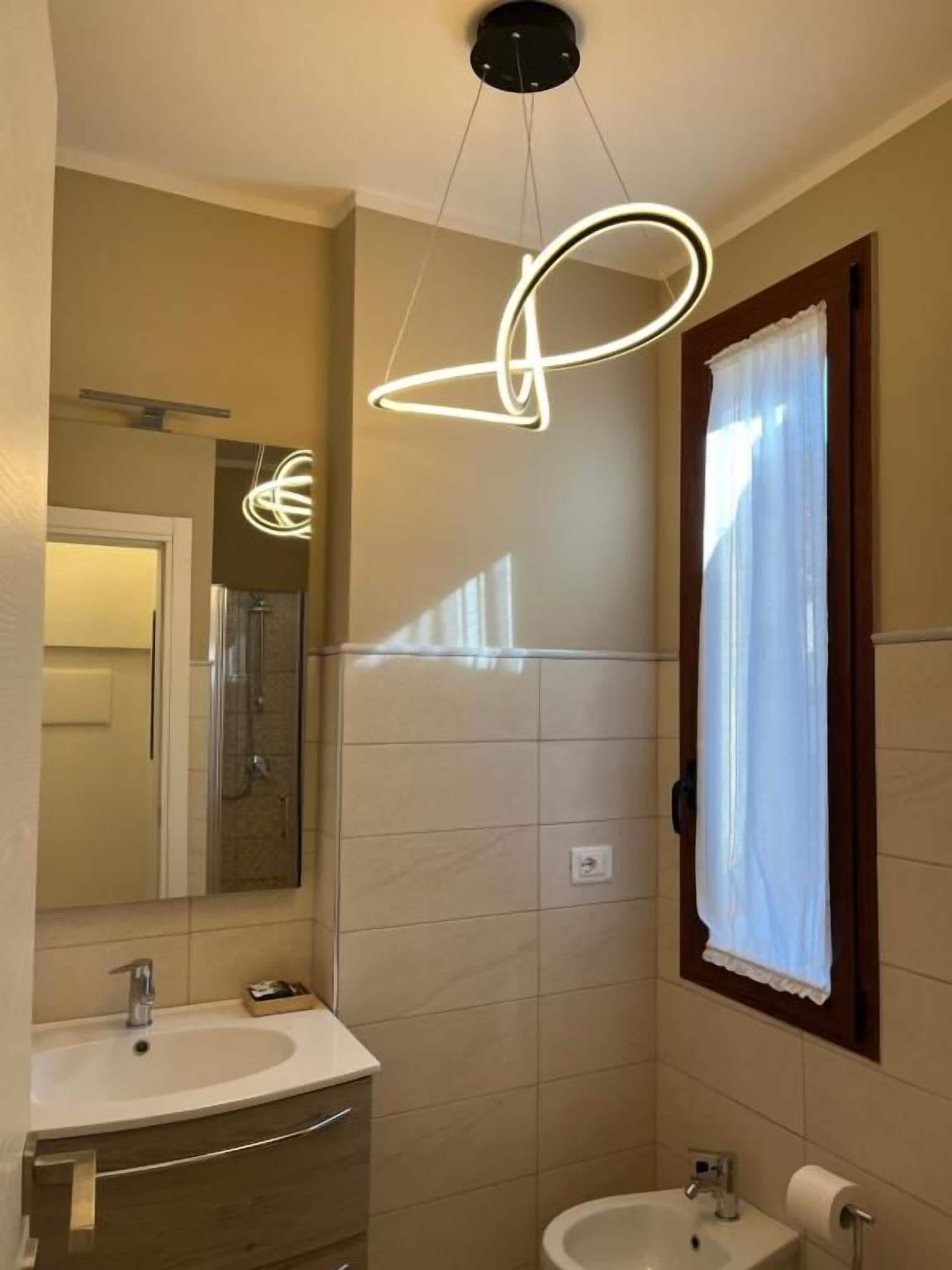 A bathroom with a sink, mirror, and a window with a curtain.
