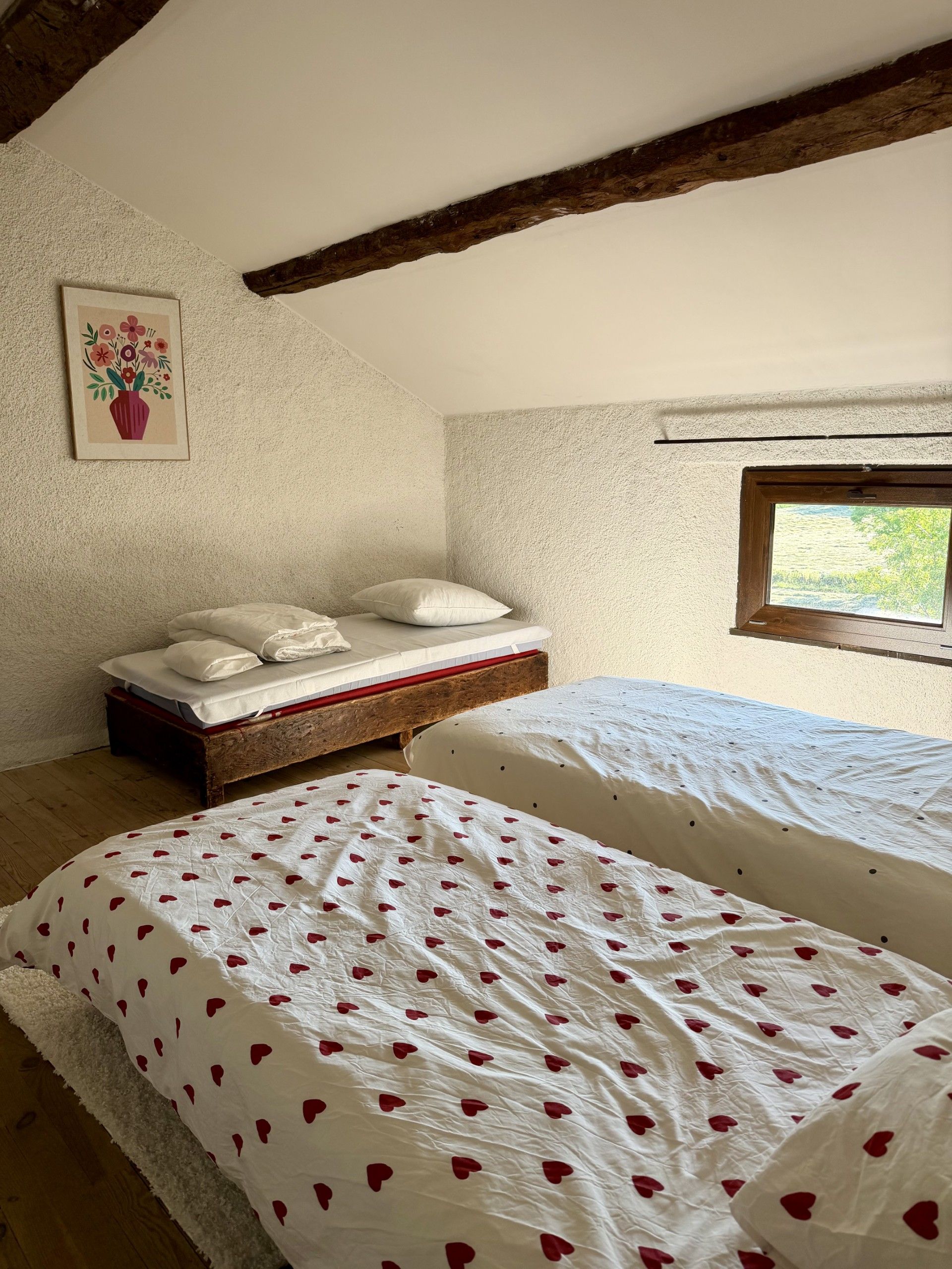 A bedroom with two beds, a wooden headboard, a window, and a wall-mounted picture.