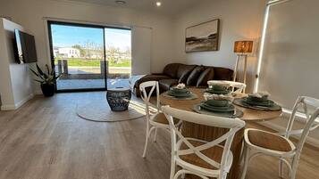 A dining area with a wooden table set for four, surrounded by white chairs.