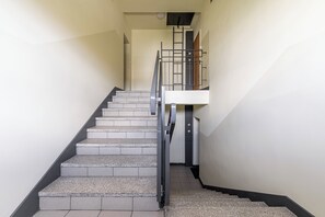 A staircase with a metal railing, leading to a landing with a door and a small window. - Lumina 3r Apart w/ AC, Parking, Balcony (Warszawa)