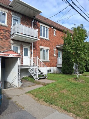 A two-story brick building with a white exterior, a garage, and a small front yard.