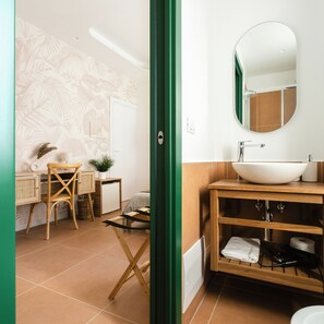 Un baño con tocador de madera, espejo redondo y lavamanos blanco.