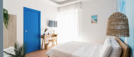 A bedroom with a bed, a desk, a chair, a television, and a window with curtains.