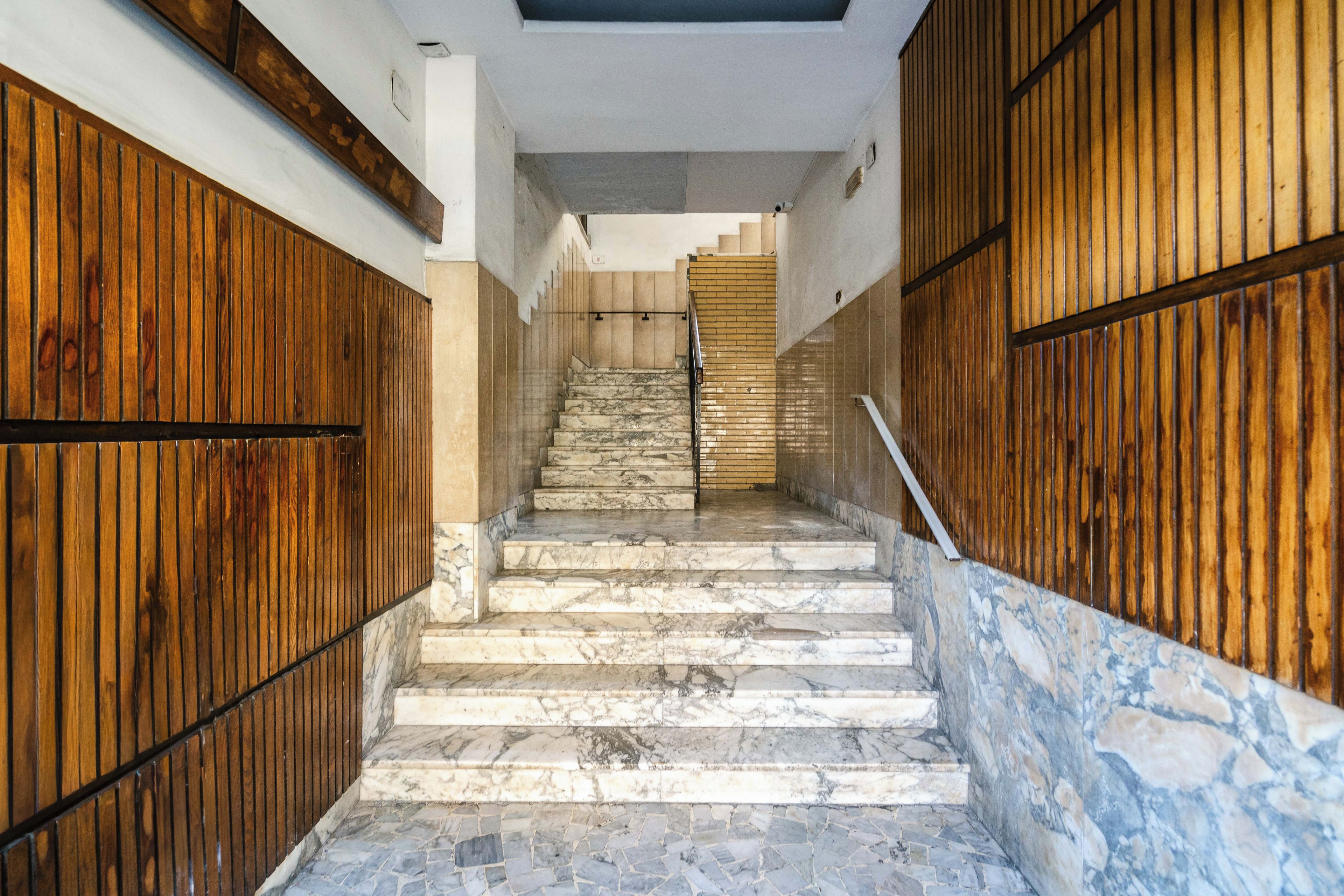 Una escalera con escalones de mármol que conduce a una plataforma, flanqueada por paneles de madera a ambos lados.