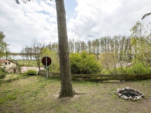 Eine natürliche Landschaft mit einem Baum, einem runden Schild und einer Feuerstelle aus Stein.
