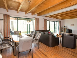 A spacious living area with a wooden ceiling, a dining table with chairs, a sofa, and a television on a stand. - Holiday Home Waldschneise A at Jabeler See (Jabel)