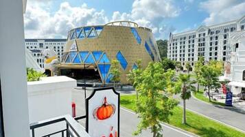 A hotel with a balcony overlooking a road and a building with a geometric facade.