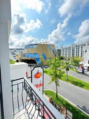Un hotel con balcón que da a una calle y un edificio de fachada geométrica.