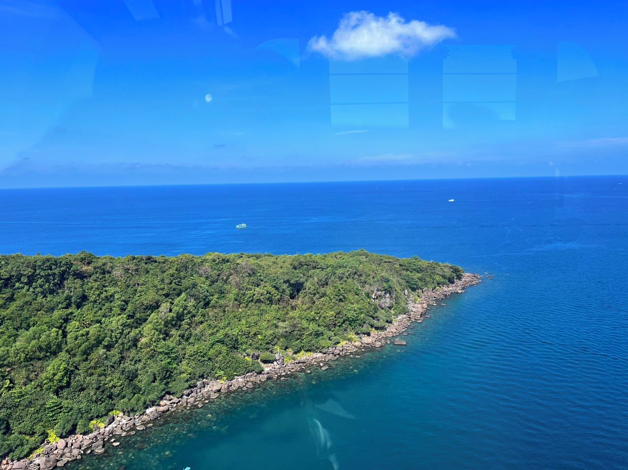 A coastal landscape with a rocky shoreline and dense greenery.