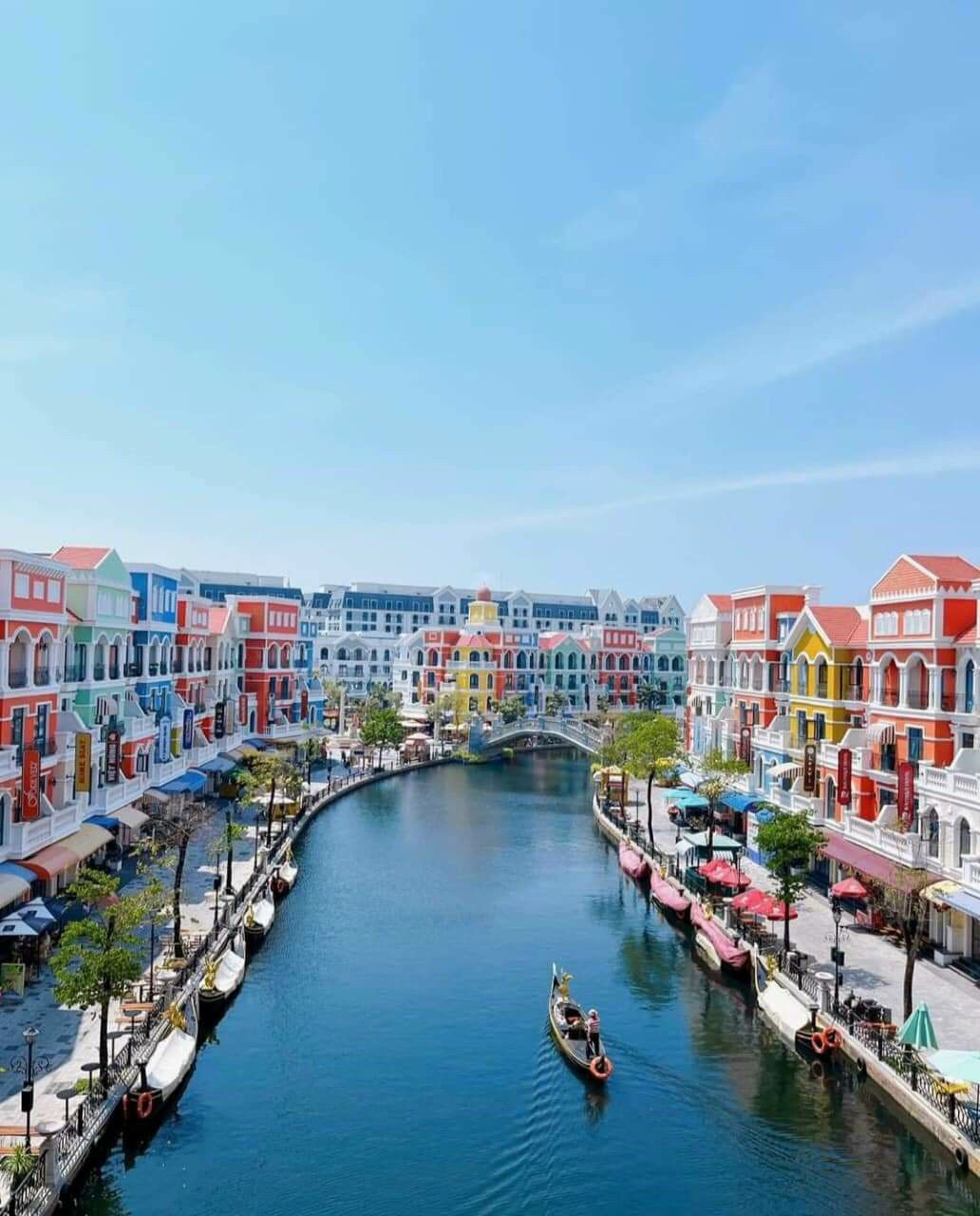 A canal with colorful buildings on either side, a bridge, and a gondola in the water.