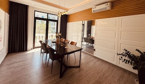 A modern dining area with a glass table, chairs, and a view of the outdoors. - Teddy Pumpkin Homestay-Grand World (Phu Quoc)