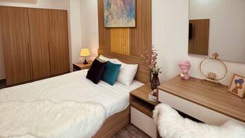 A modern bedroom with a bed, bedside table, lamp, and a mirror.