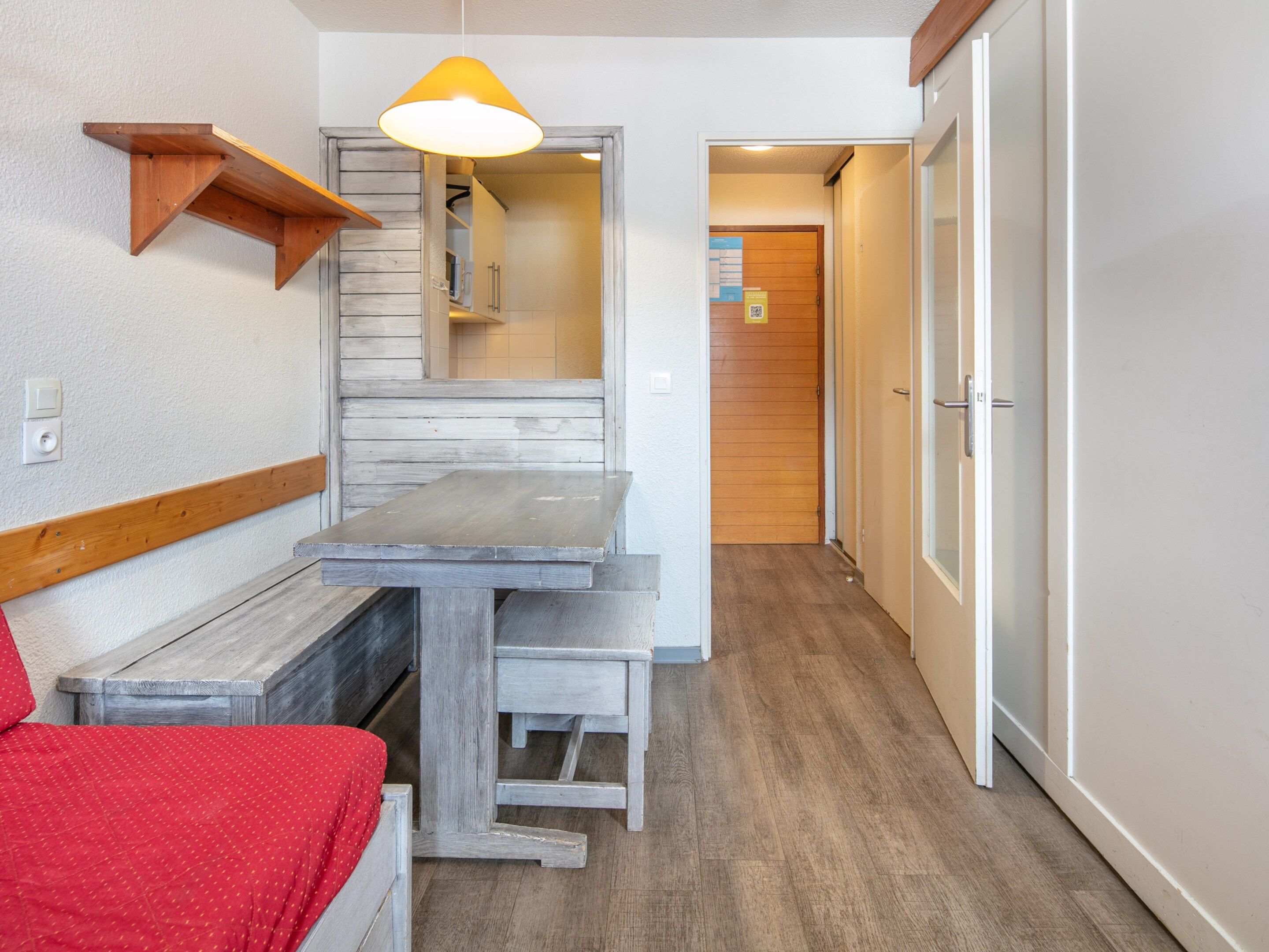 A compact room with a wooden bench, a small table, and a hanging light fixture.