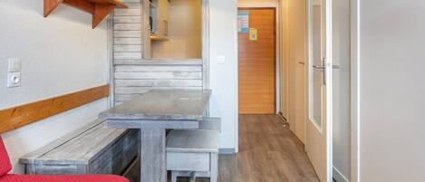 A compact room with a wooden bench, a small table, and a hanging light fixture.