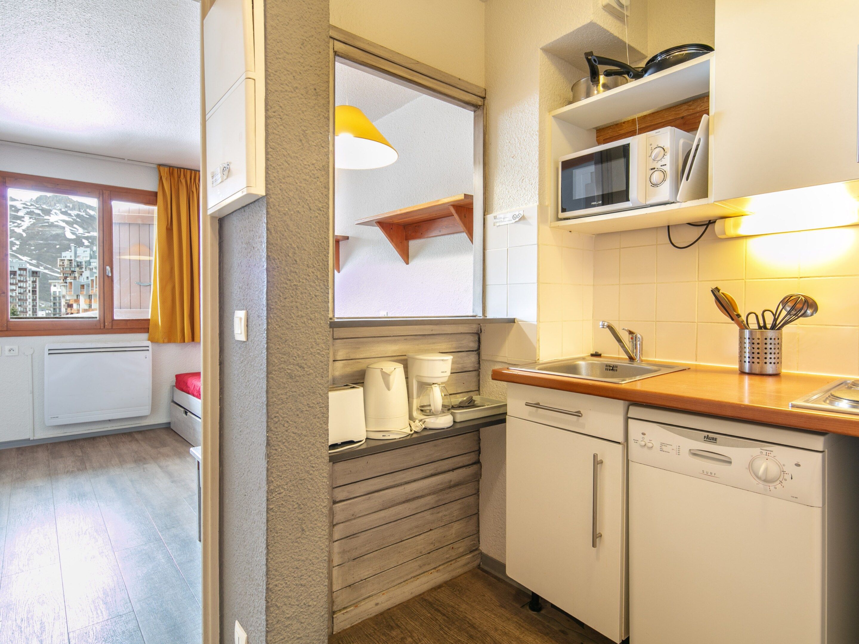 A compact kitchen with a microwave, coffee maker, and dishwasher.