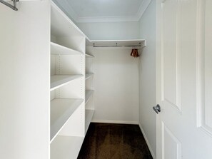 A walk-in closet with open shelves and a hanging rod. - St Pauls Comfort Home (Wagga Wagga)
