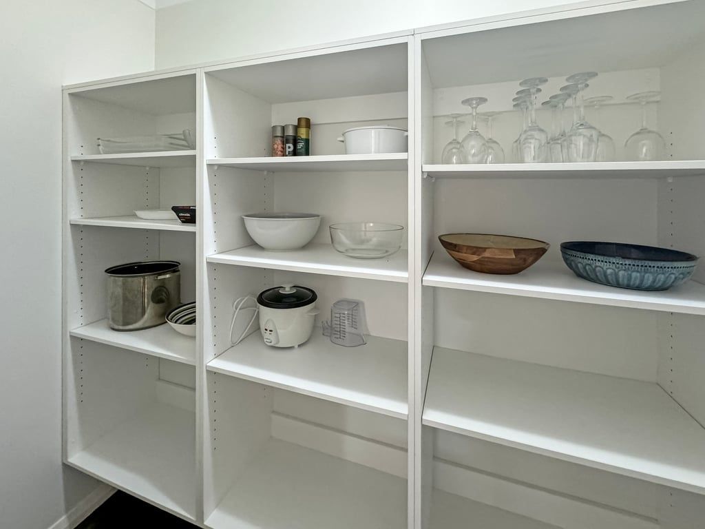 A white shelving unit with various kitchenware items.
