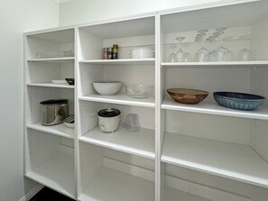 A white shelving unit with various kitchenware items.