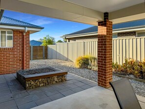A patio area with a fire pit, a chair, and a brick wall. - St Paul's - Sleeps 8 (Wagga Wagga)