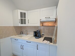 A compact kitchen with white cabinets, a built-in oven, a coffee maker, and a toaster. - Studio with pool, shared garden - 2 guests (Argenton-sur-Creuse)