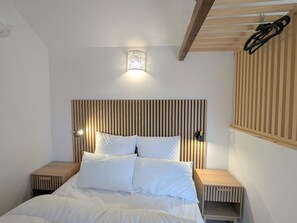 A bedroom with a wooden slat headboard, a bed with white bedding, two bedside tables, and a hanging light fixture. - Studio with pool, shared garden - 2 guests (Argenton-sur-Creuse)