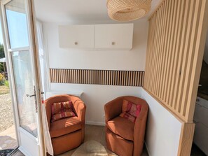 A room with two brown armchairs, a woven light fixture, and a white wall with a black horizontal stripe. - Charming studio in Val de Creuse (Argenton-sur-Creuse)