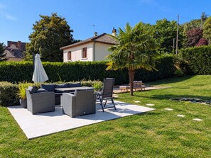 A patio with outdoor furniture, a palm tree, and a hedge. - Charming studio with garden - 2 guests (Argenton-sur-Creuse)