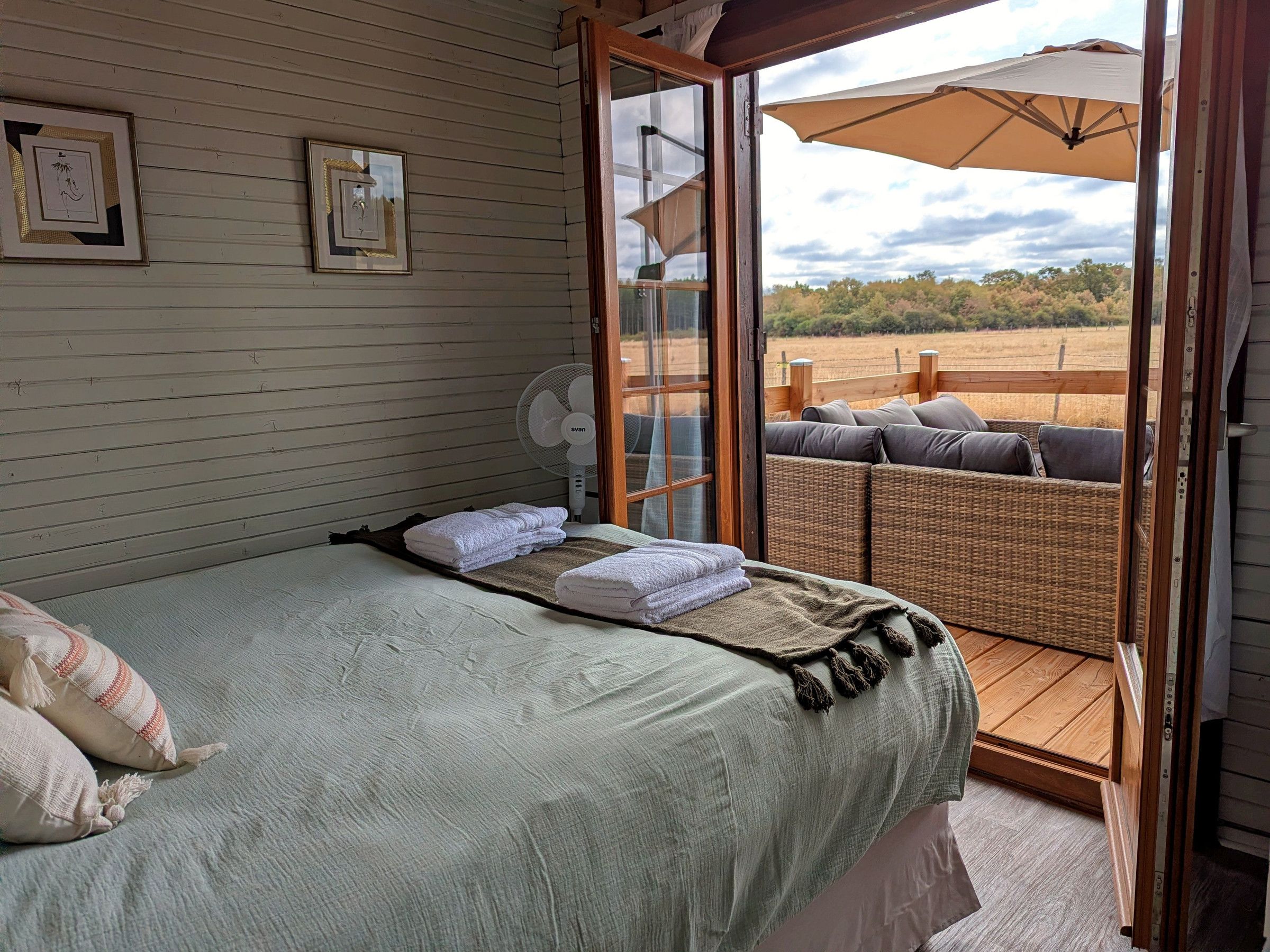 A bedroom with a bed, a fan, and a view of the outdoors.