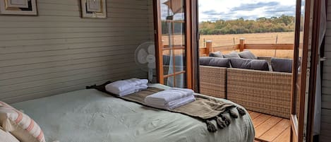 A bedroom with a bed, a fan, and a view of the outdoors.