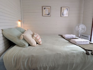 A bed with pillows, a fan, and towels. - Cozy chalet in nature - 6 guests (Ligny-le-Ribault)