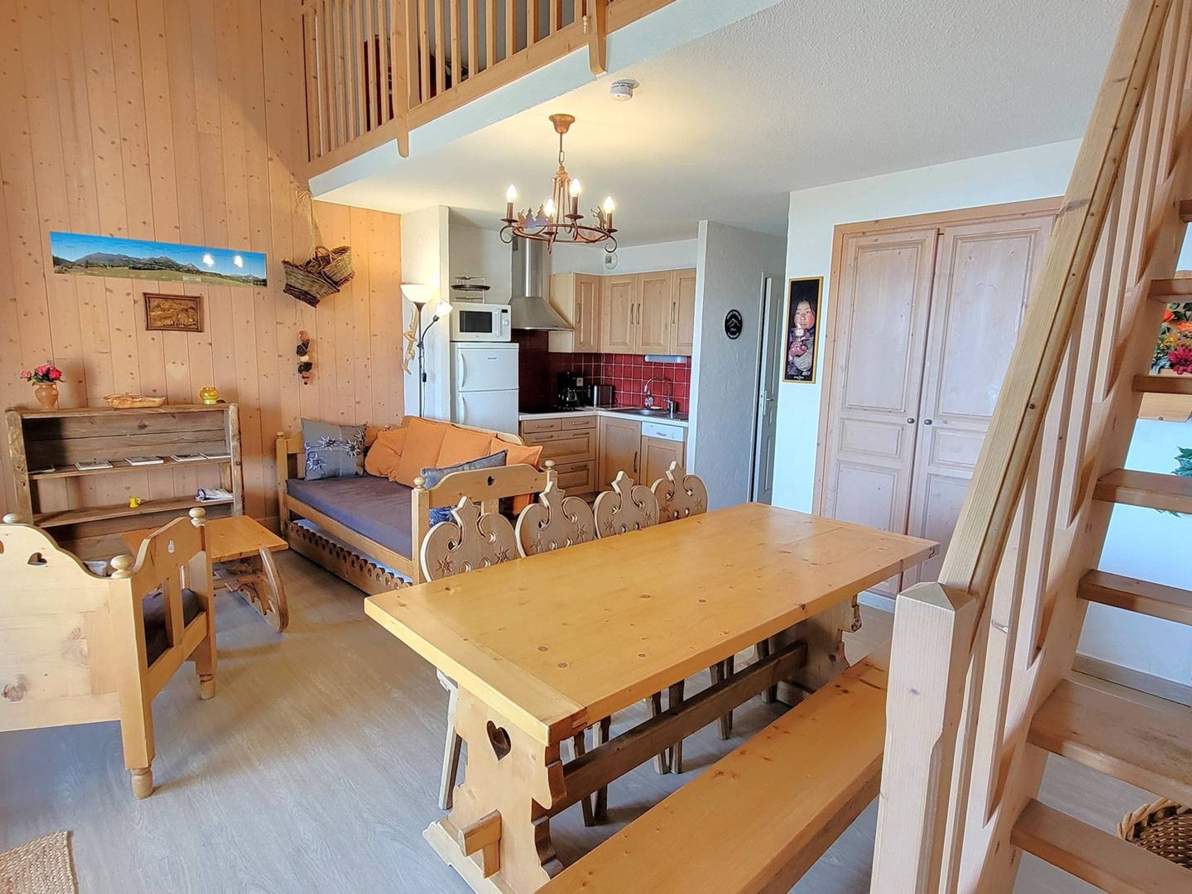 A cozy room with a wooden dining table, a sofa, and a kitchen area with cabinets and a microwave.