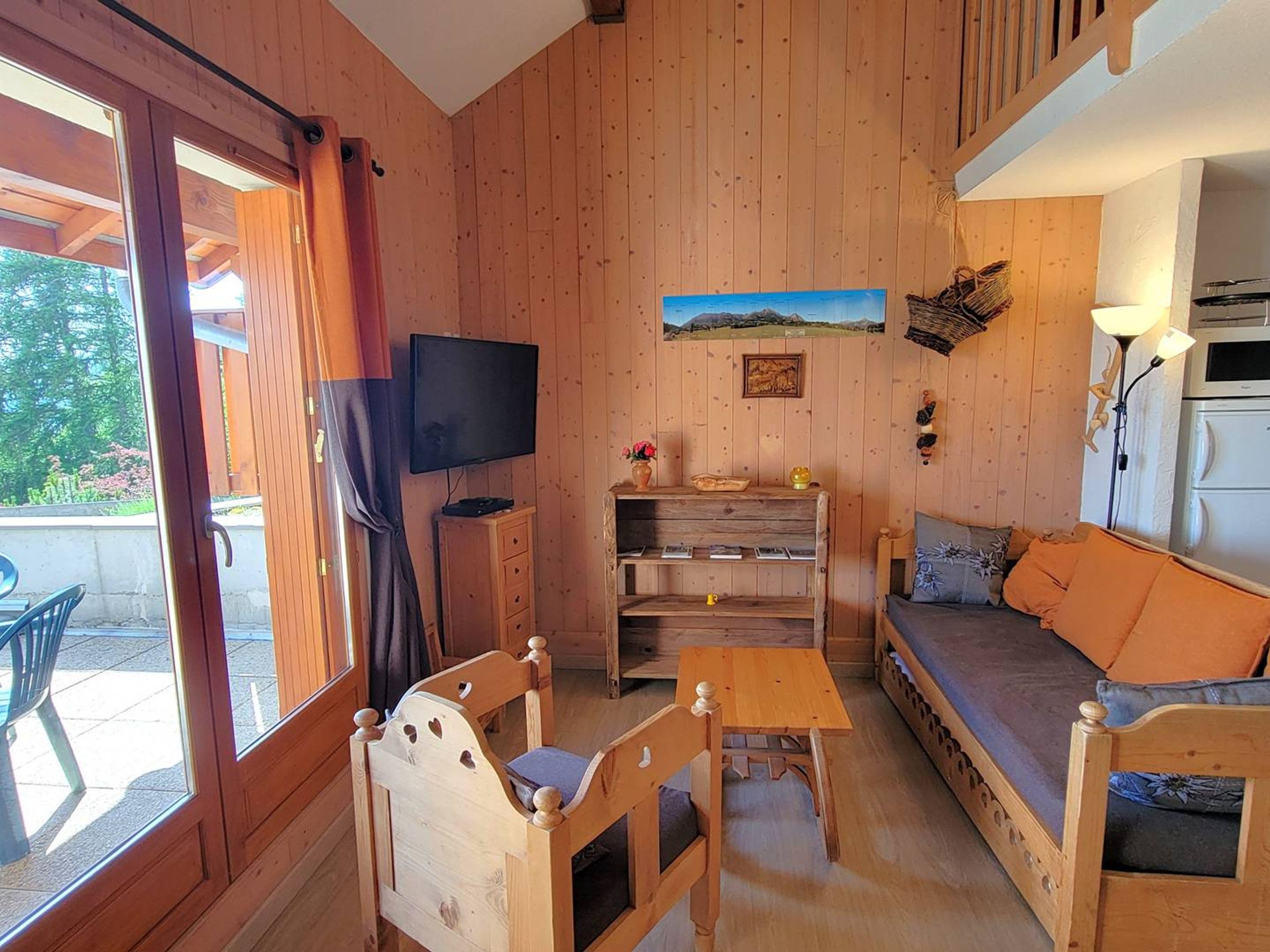 Een houten interieur met een bank, een televisie, een tafel en een stoel.