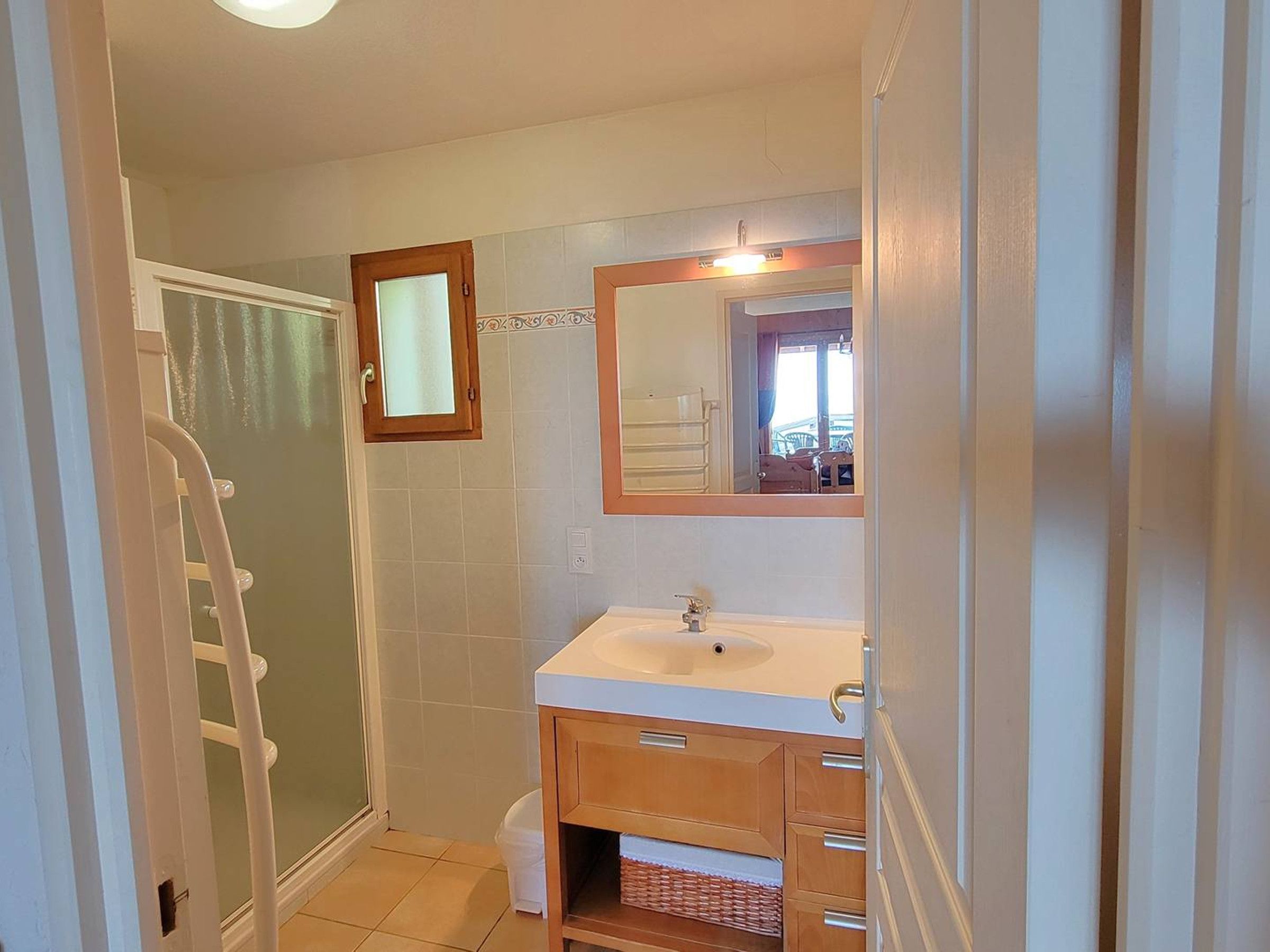 A bathroom with a white sink, a mirror, and a shower area.