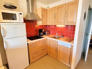 A compact kitchen with a white refrigerator, a microwave, a stove, and wooden cabinets.