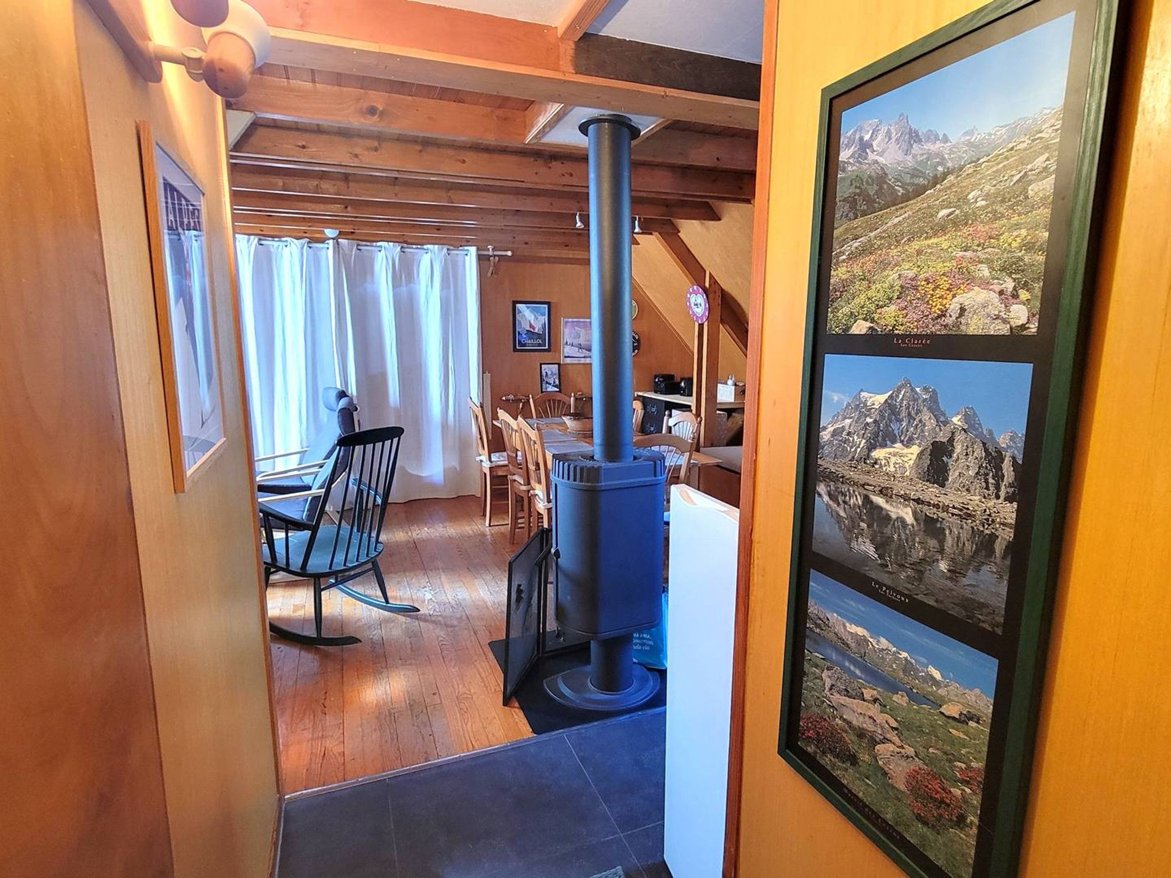 Un interior de madera acogedor con una zona de comedor, un ventanal con cortinas y una chimenea.