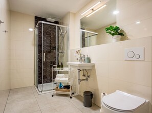 Un bagno moderno con box doccia in vetro, lavandino bianco e water.